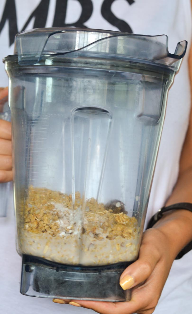 Shalva holding a Vitamix container with oatmeal pancakes ingredients inside.