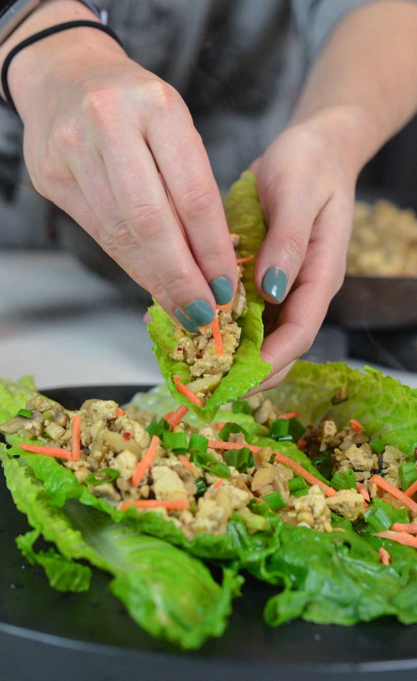 Asian lettuce wraps being assembled by pretty woman hands.