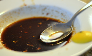 Brown Spicy Soy Fish Sauce with Chili Pepper Flakes served in white bowl and spoon