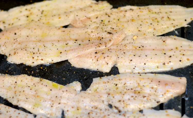 Uncooked Dover Sole Fillets on broiler pan with salt pepper ready to be cooked