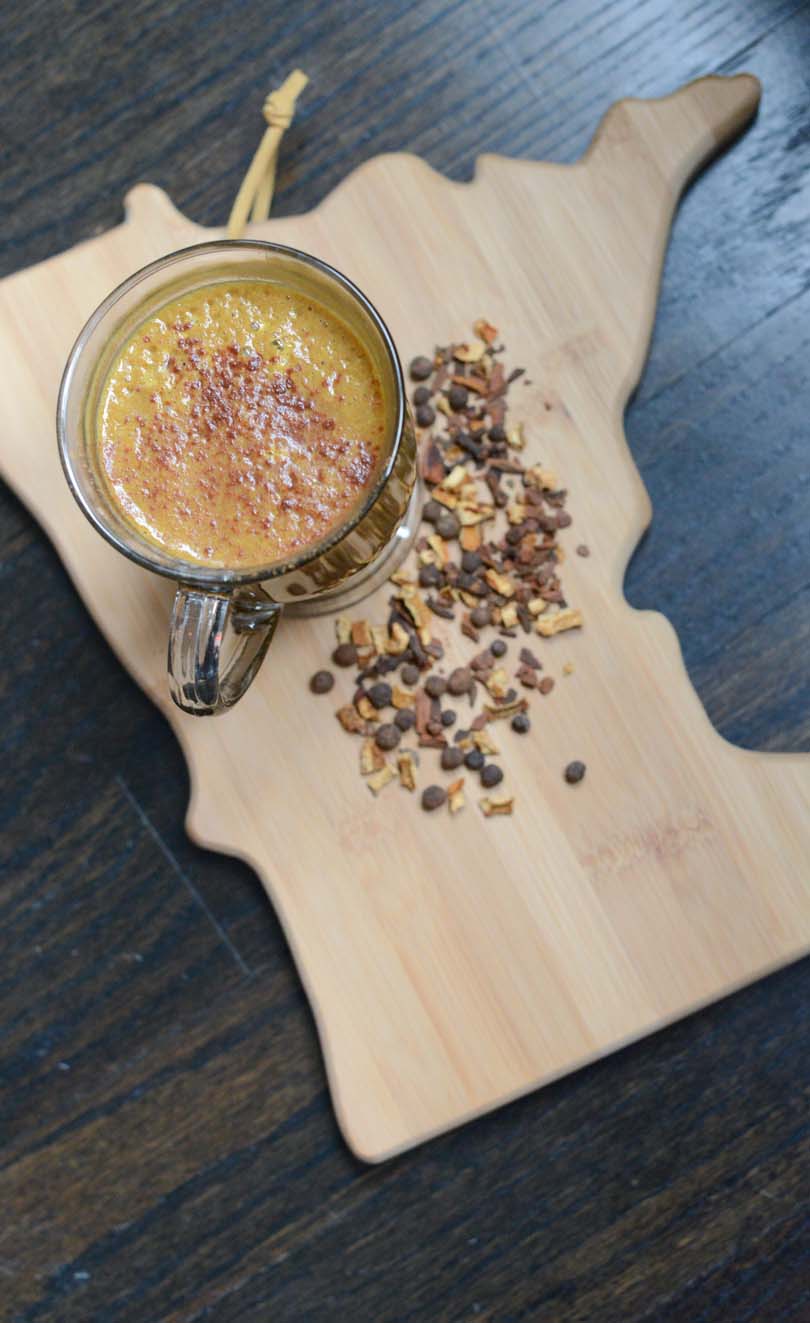 Pumpkin spice latte on Minnesota cutting board with seasoning sprinkled around.