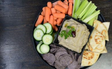 Black olive hummus served with vegetables, pita, and chips.