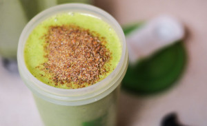 A birds eye view of a smoothie with ground flaxseed on top, ready to be mixed in by hand. 