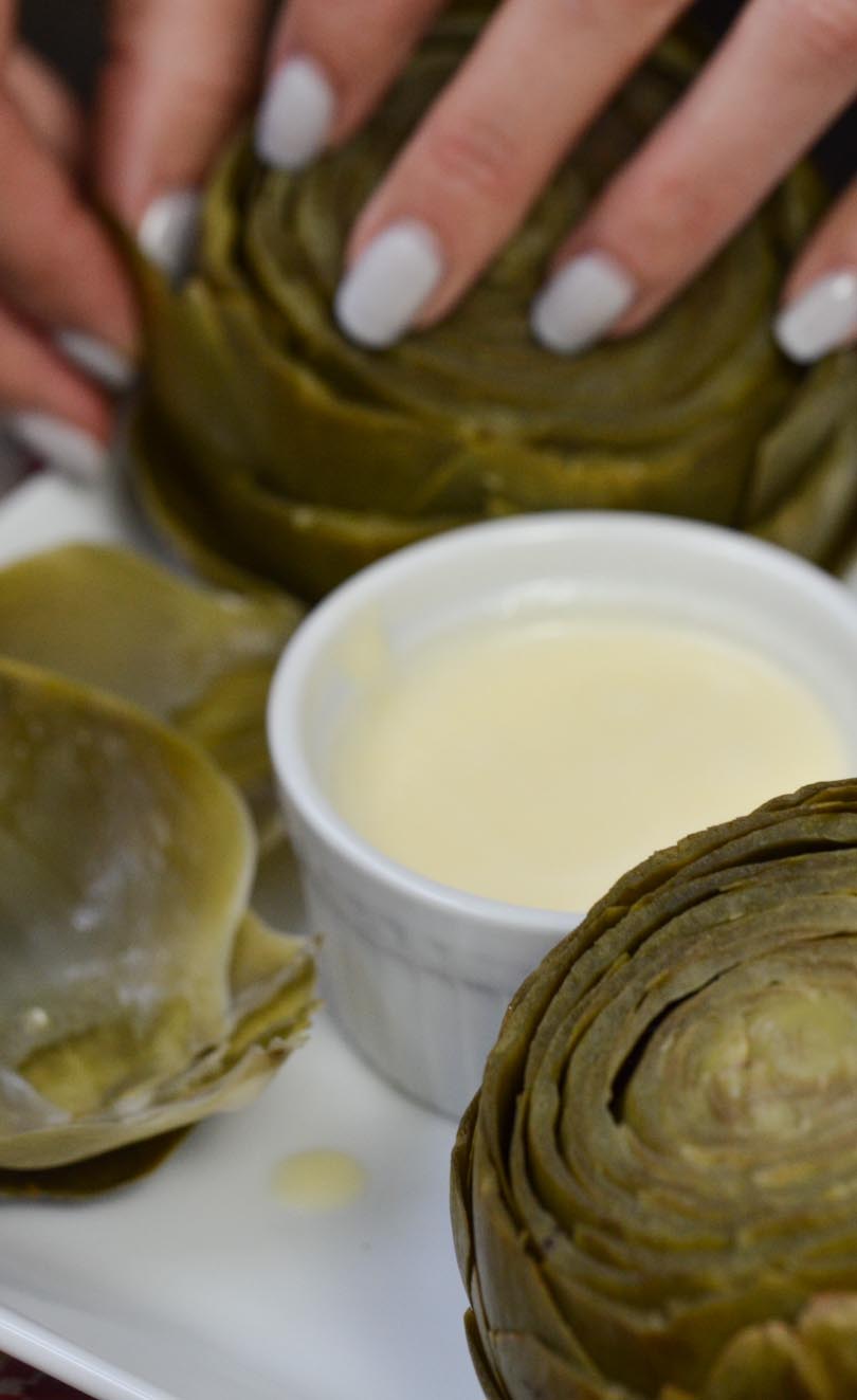 Artichoke with dish of vegan garlic butter dipping sauce made in our Vitamix.