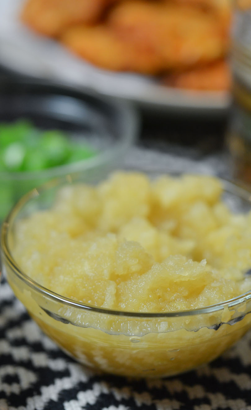 Apple sauce served with latkes in background.