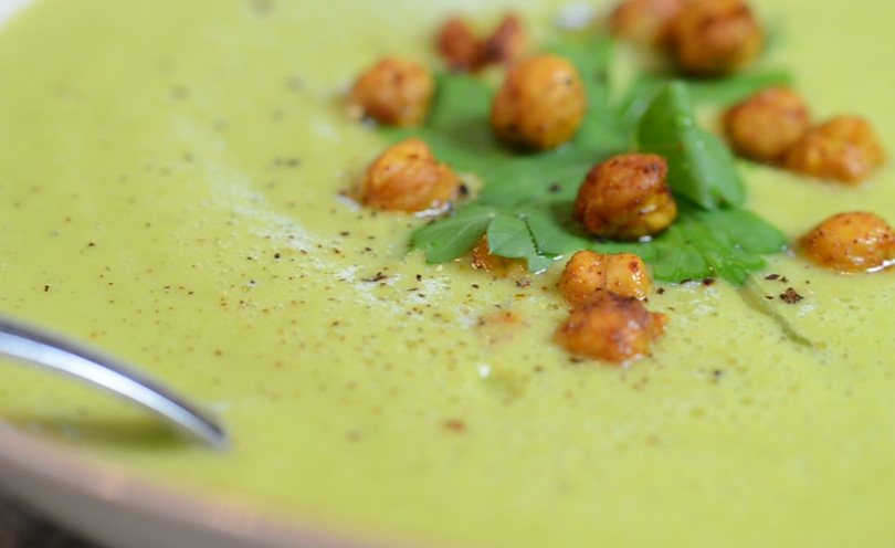 Super closeup of a zucchini coconut soup garnished with roasted chickpeas and parsley.