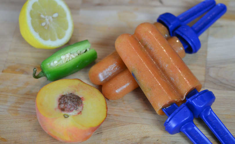 Two peach jalapeño popsicles with their ingredients.