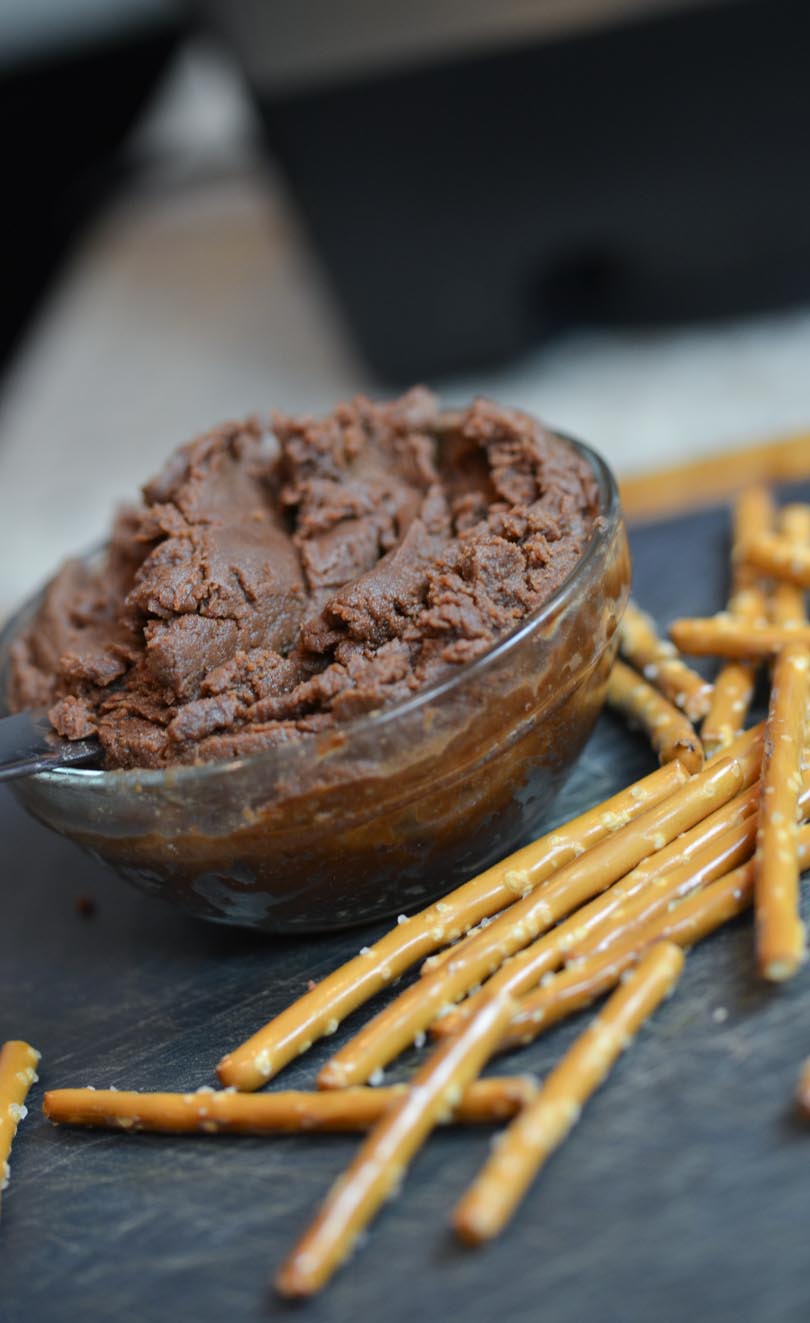Vertical look at chocolate almond butter served with pretzel sticks