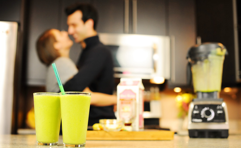 Lenny Gale and Shalva Geffen in the background of two green smoothies and a Vitamix Pro 750.
