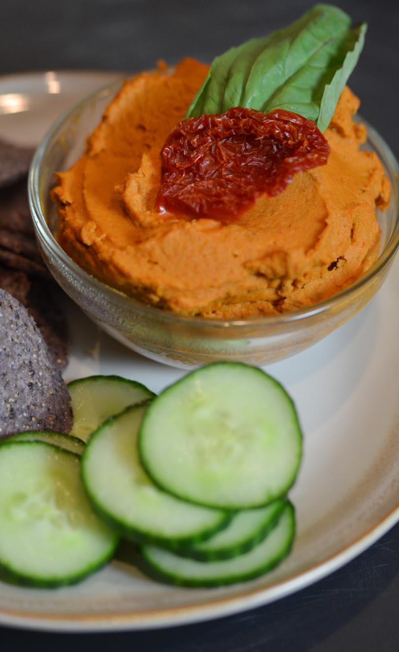 Sun dried tomato basil hummus served with cucumbers and blue tortilla chips.