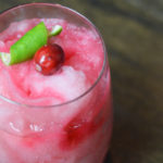 Merry mule, a frozen, pink beverage garnished with cranberry and lime garnish.