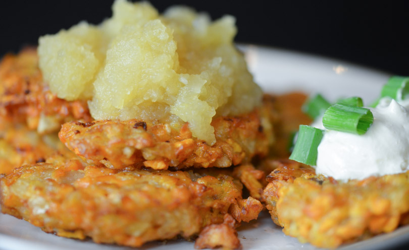 Sweet potato latkes with apple sauce on top and sour cream on side.