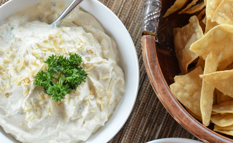 French onion dip served next to a bowl of salty tortilla chips.