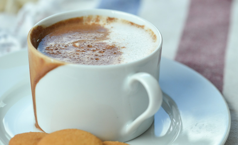 Mexican hot chocolate served in white mug with vanilla cookies.