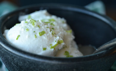 A scoop of coconut lime sorbet served in a black bowl.