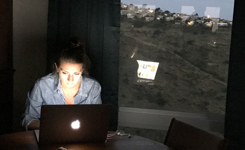 Shalva working on her Macbook with Honolulu in the background.