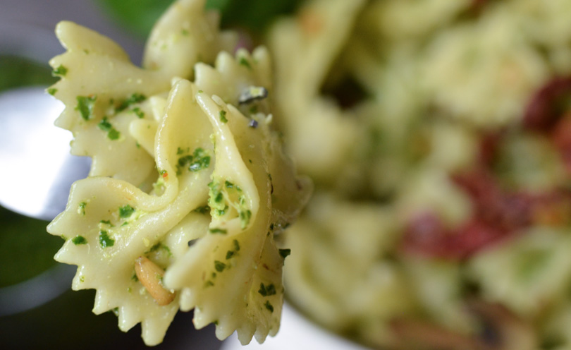 Fork full of bow tie pasta with pesto.