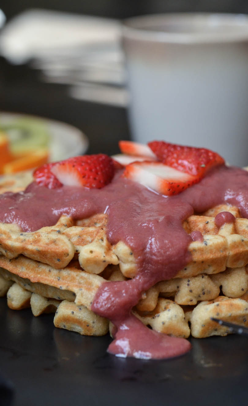 Strawberry topping on waffles with coffee.
