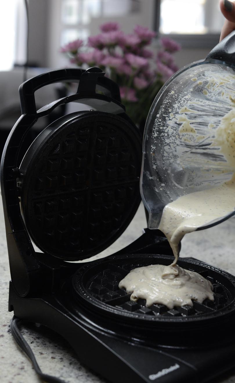 Pouring waffle batter from Vitamix container onto waffle iron.