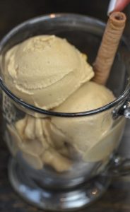 Coffee ice cream served in clear mug with a cookie stick.