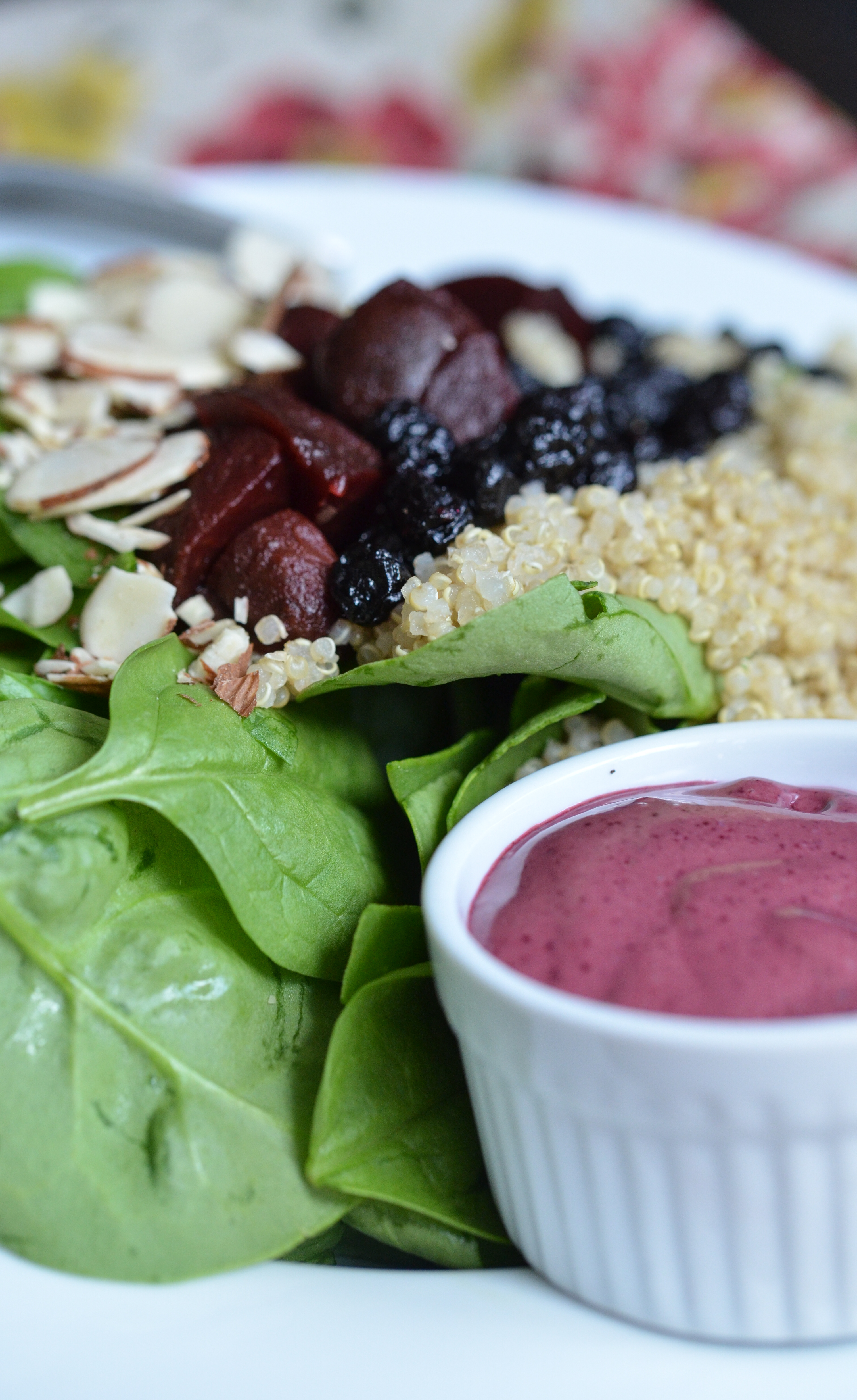 A side of blueberry vinaigrette with a spinach and beet salad.