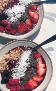 Acai bowls with strawberries, granola, and chia seeds on top.
