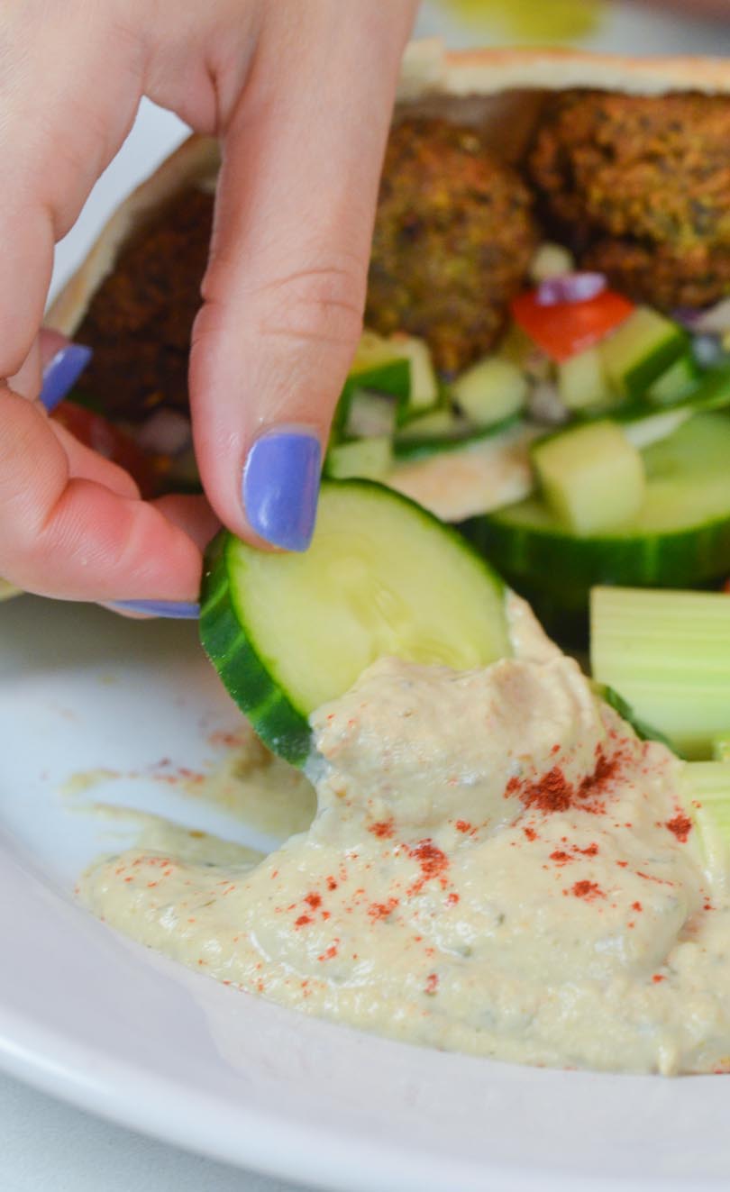 Dipping a cucumber slice into baba ghanoush.