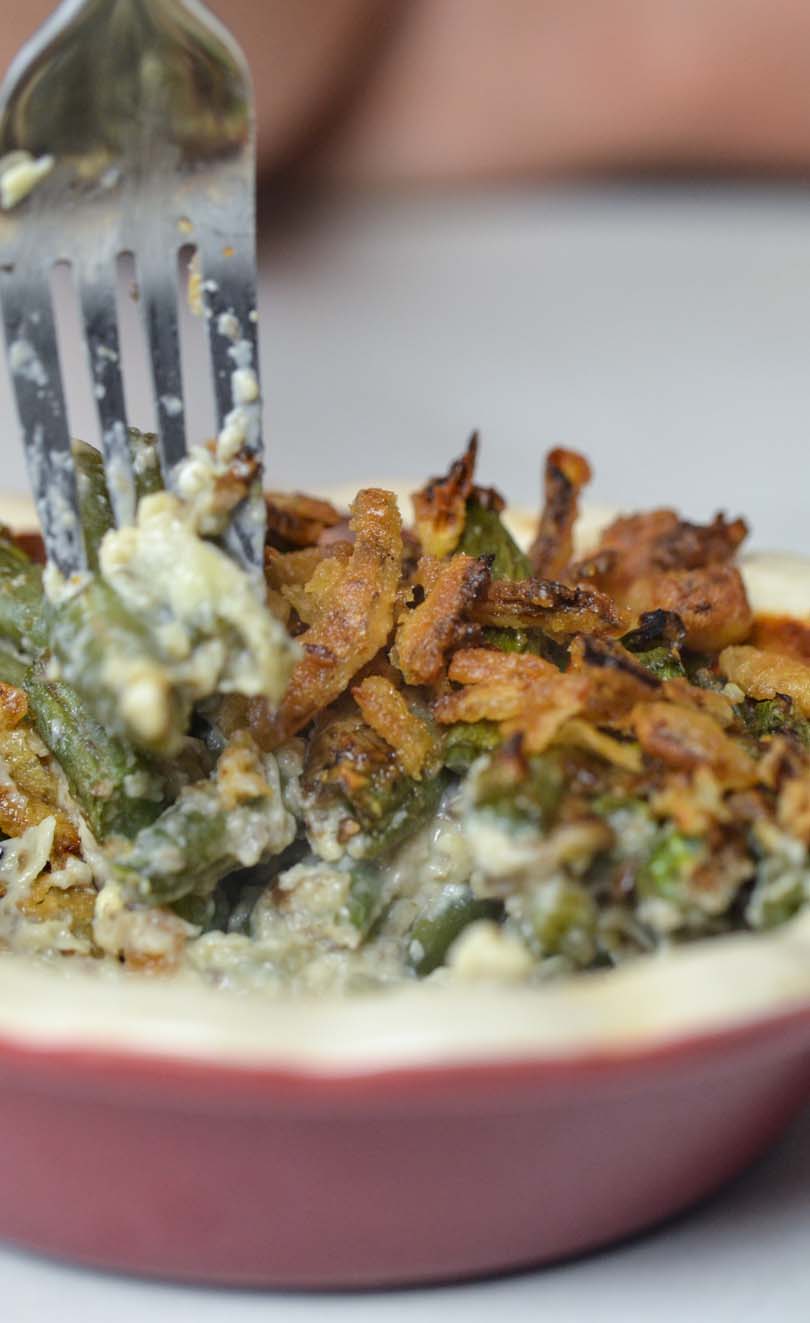 Green bean casserole being tasted with a fork.