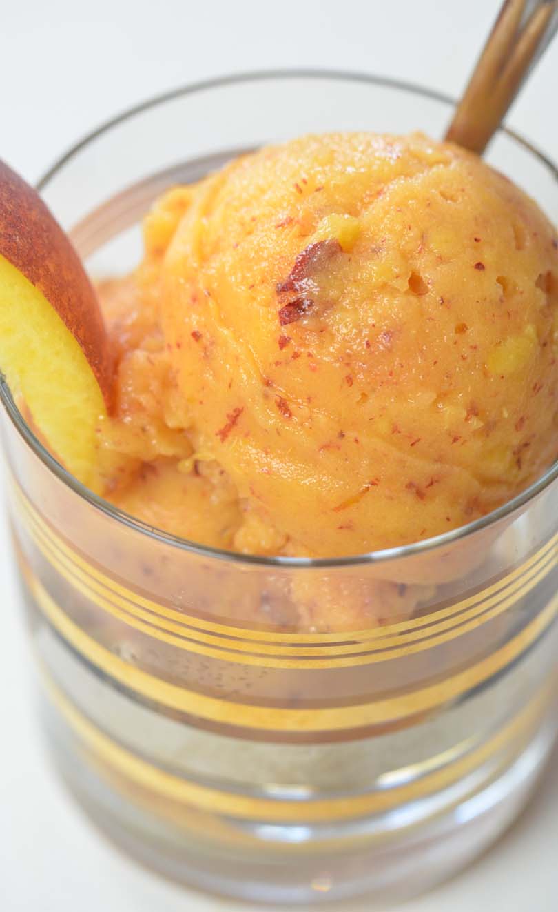 Peach buzz sorbet served in a fancy low glass with a spoon.