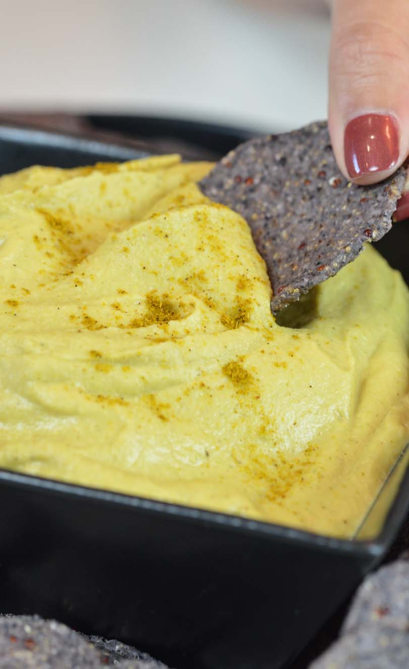 Thai curry hummus getting dipped by a chip.