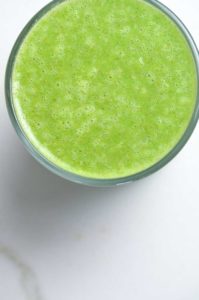 Overhead view of a tall glass of green juice.