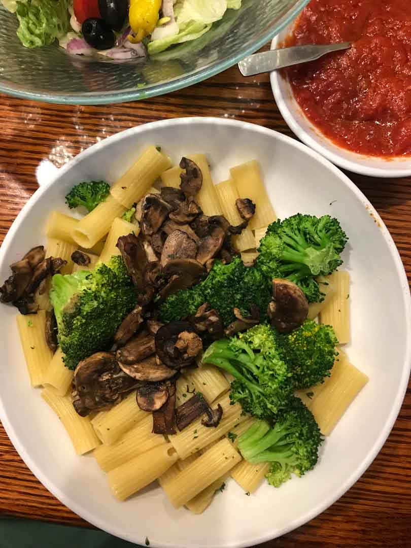 Plant-based olive garden order of pasta with marinara and mushrooms and steamed broccoli.
