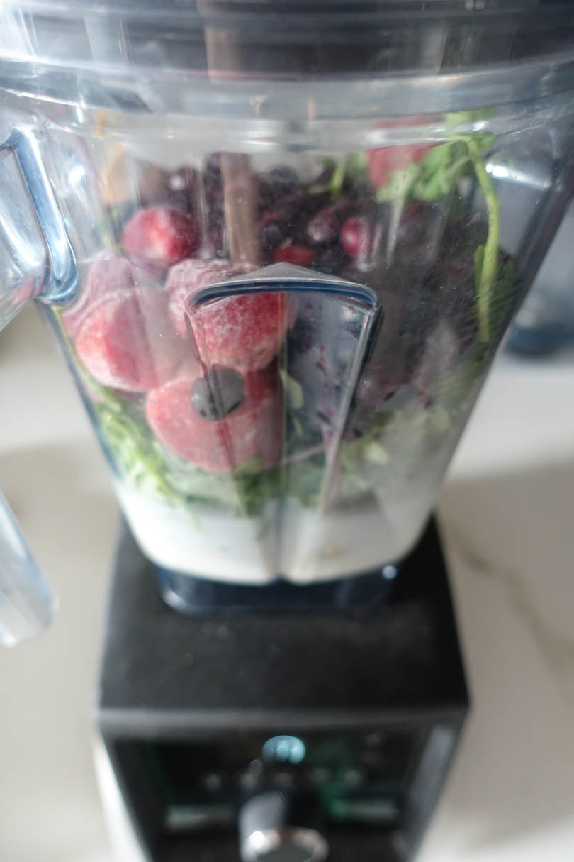 Frozen strawberries blueberries peanut butter and greens in a Vitamix A3500. 