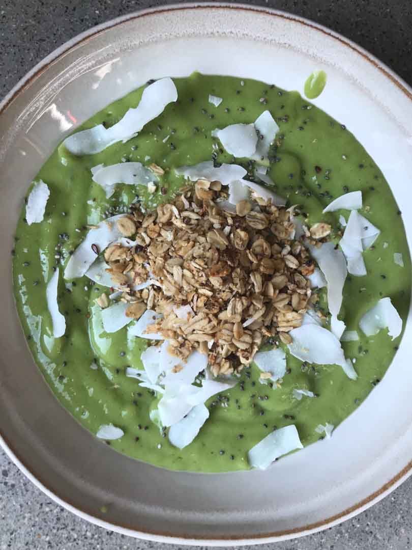 Green smoothie bowl with toppings sprinkled.