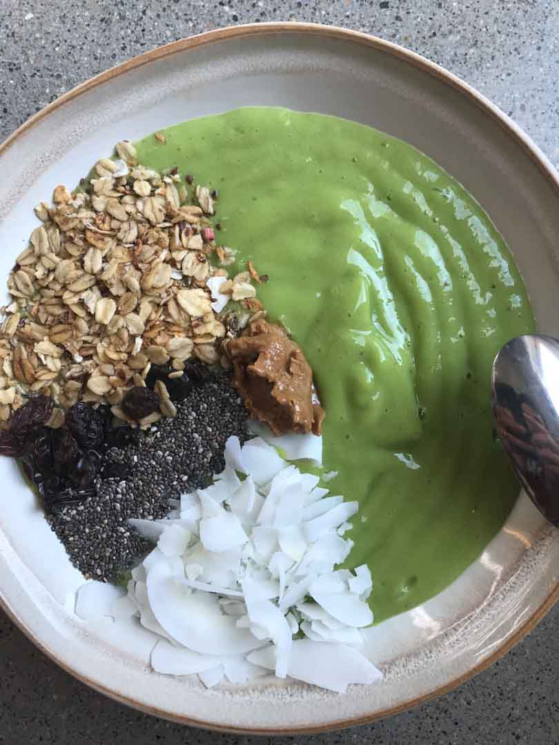 Green smoothie bowl with toppings in sections.