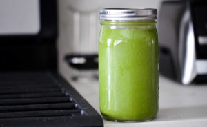 Green juice in a jar in front of a Vitamix A3500