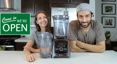 Shalva and Lenny Gale with Vitamix A3500 and 48 oz container for Life is No Yoke with a "come we're open" sign.