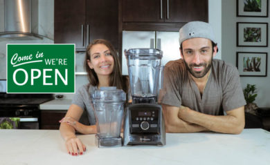 Shalva and Lenny Gale of Life is No Yoke with a Vitamix and we're open sign.
